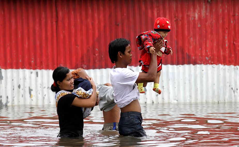 A man carrying his baby walks through flood waters A man carrying his baby walks through flood waters
