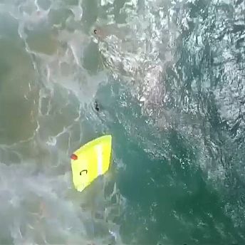 Lifeguard drone dropping float into water close to two swimmers in trouble