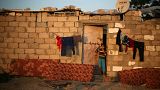 A Palestinian girl stands outside her family house in Gaza