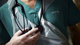 FILE - A junior doctor holds his stethoscope during a patient visit on Ward C22 at the Royal Blackburn Teaching Hospital, in Blackburn, England,