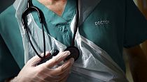FILE - A junior doctor holds his stethoscope during a patient visit on Ward C22 at the Royal Blackburn Teaching Hospital, in Blackburn, England,