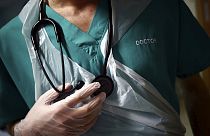 ARQUIVO - Um médico em formação segura o seu estetoscópio durante uma visita a um doente na ala C22 do Royal Blackburn Teaching Hospital, em Blackburn, Inglaterra,