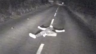 Watch: Drunk man seconds from death after lying down in middle of British road