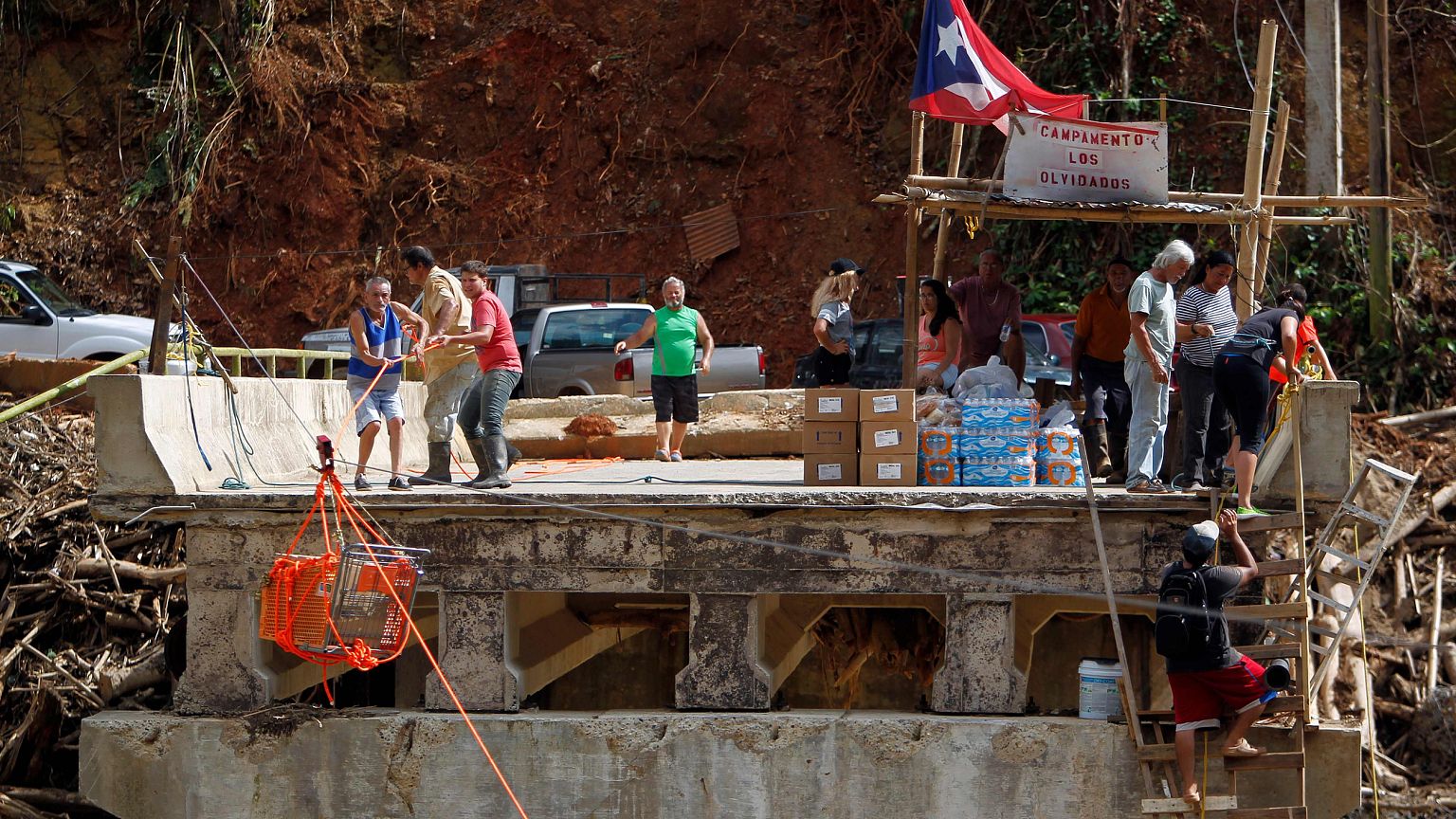 Image: A group of people use a shopping cart with an improvised pulley syst