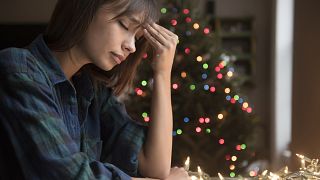 Image: A woman sits by a Christmas tree