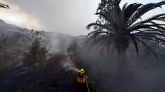 Image: A firefighter puts out hotspots on a smoldering hillside in Montecit
