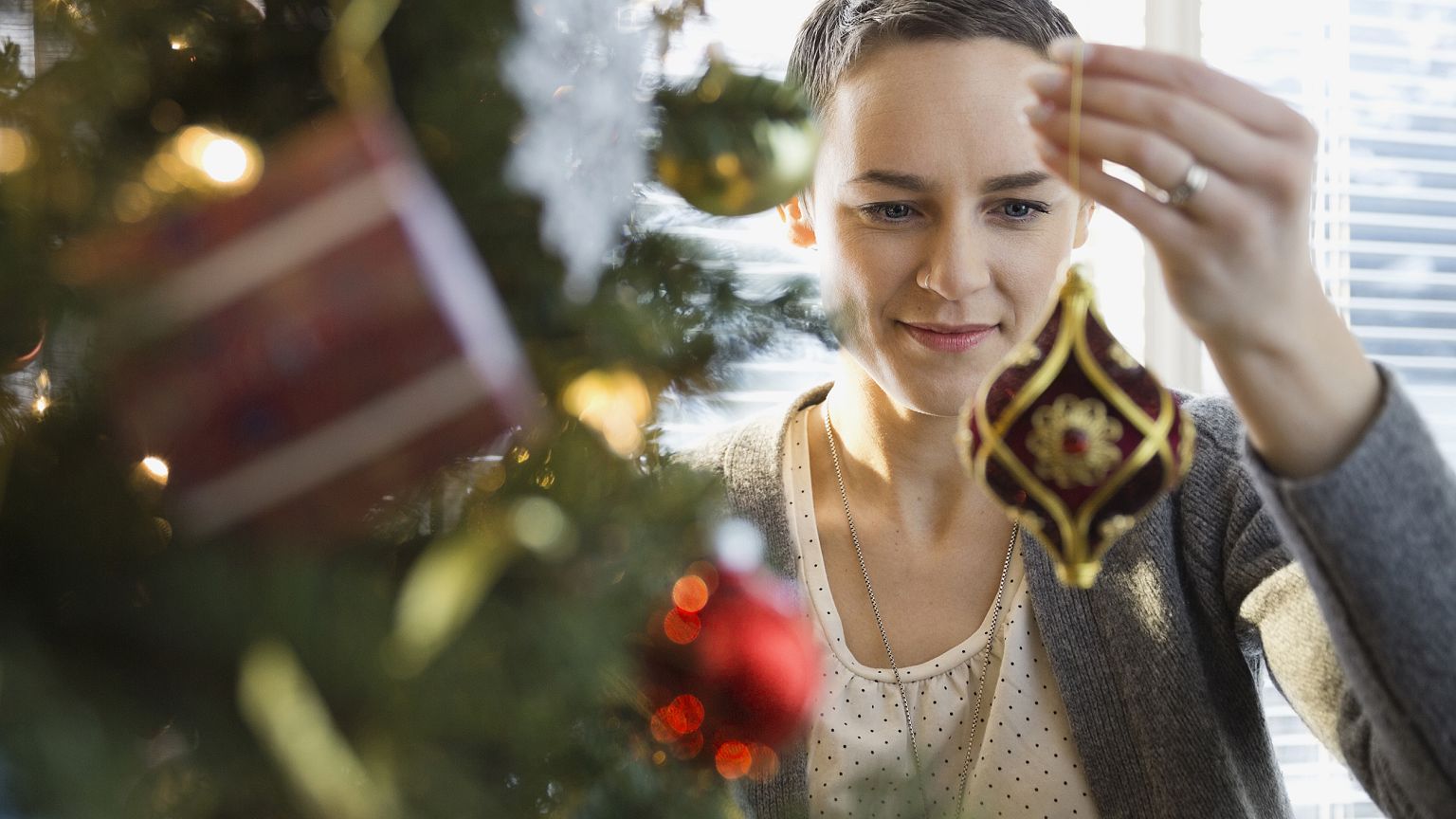 Image: A woman decorates a Christmas tree at home