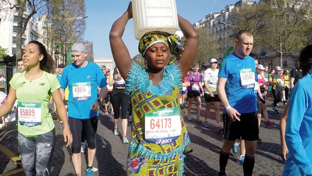 Woman carries can of water on her head along Paris marathon