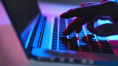 Image: Silhouette of male hand typing on laptop keyboard at night