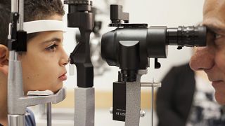 Image: A doctor checks the eyes of a patient who received a blindess gene t