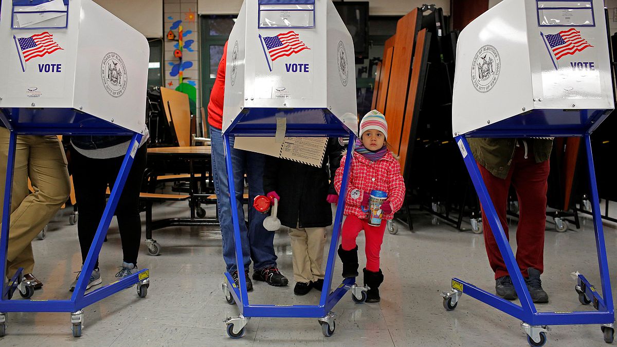 Image: Myla Gibson, 3, waits as her father Ken Gibson fills out a ballot fo