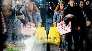 Image: People carry shopping bags outside a shopping mall