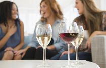 Image: Women drinking wine and talking on sofa in living room