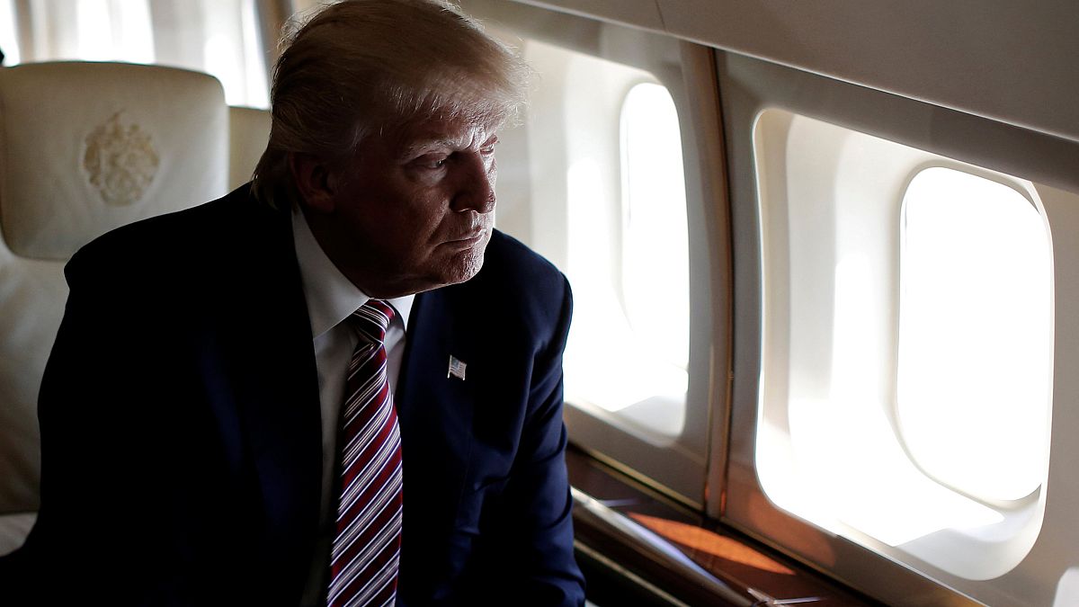 Image: Trump looks out the window as he travels aboard his plane between ca