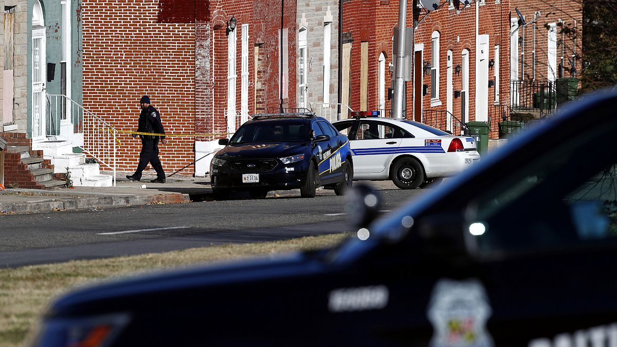 Image: An officer walks behind a police line near the scene of a shooting