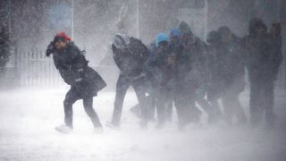Image: People struggle to walk in the blowing snow during a winter storm