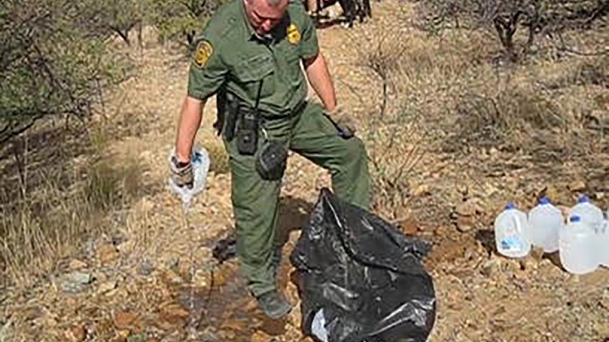 Image: A Border Patrol agent empties a water bottle