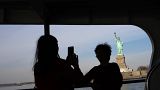 Image:  Tourists take photos of the Statue of Liberty