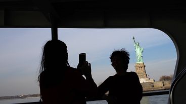 Image:  Tourists take photos of the Statue of Liberty