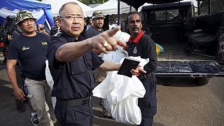 Malaysian forensic officers examine remains of migrants found along Thai border