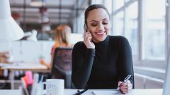 Image: A woman speaks on the phone in an office.