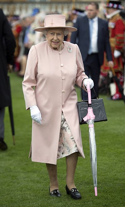 Her light pink umbrella goes with this blush-colored jacket and hat.