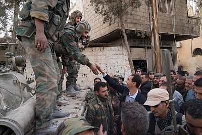 Syrian President Bashar al-Assad reaches out to shake the hand of a Syrian army soldier in eastern Ghouta, Syria on March 18, 2018