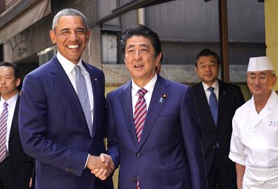 Former President Barack Obama shakes hands with Japanese Prime Minister Shinzo Abe in Tokyo\'s Ginza shopping district on Sunday.