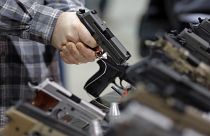 Image: A visitor holds a pistol at a gun display during a National Rifle As