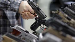 Image: A visitor holds a pistol at a gun display during a National Rifle As