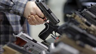 Image: A visitor holds a pistol at a gun display during a National Rifle As