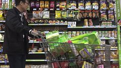 Image: A man pushes a shopping cart past a display of nuts imported from th