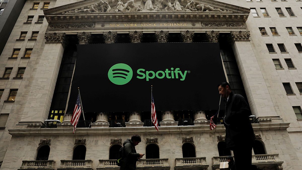 Image: Pedestrians walk past a Spotify banner on New York Stock Exchange