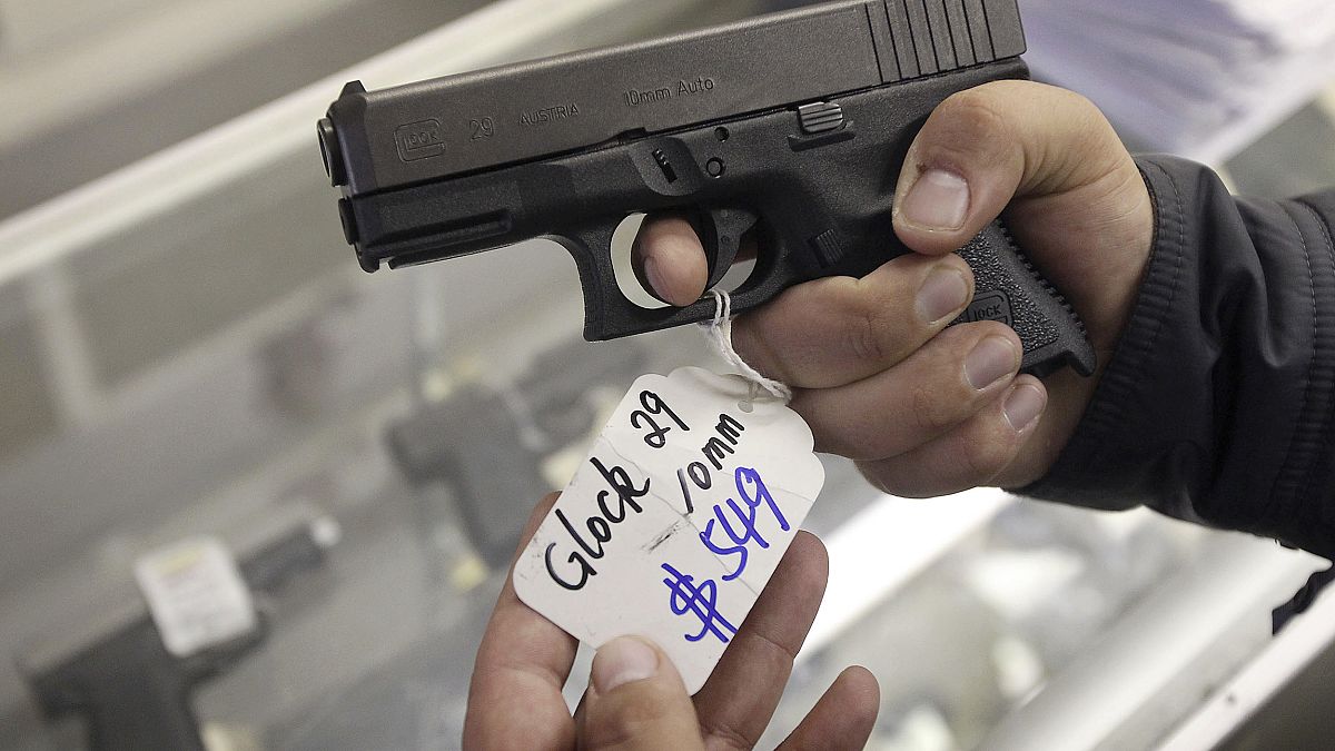 Image: A customer looks at a Glock 29 10mm hand gun at the Guns-R-Us gun sh