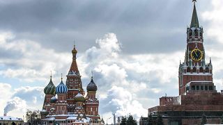 Image: People walk in front of St. Basil's Cathedral and the Kremlin on Red