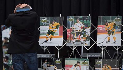 A man looks at photographs before a vigil Sunday at Elgar Petersen Arena, home of the Humboldt Broncos, to honor the victims of a fatal bus accident in Humboldt, Saskatchewan. 