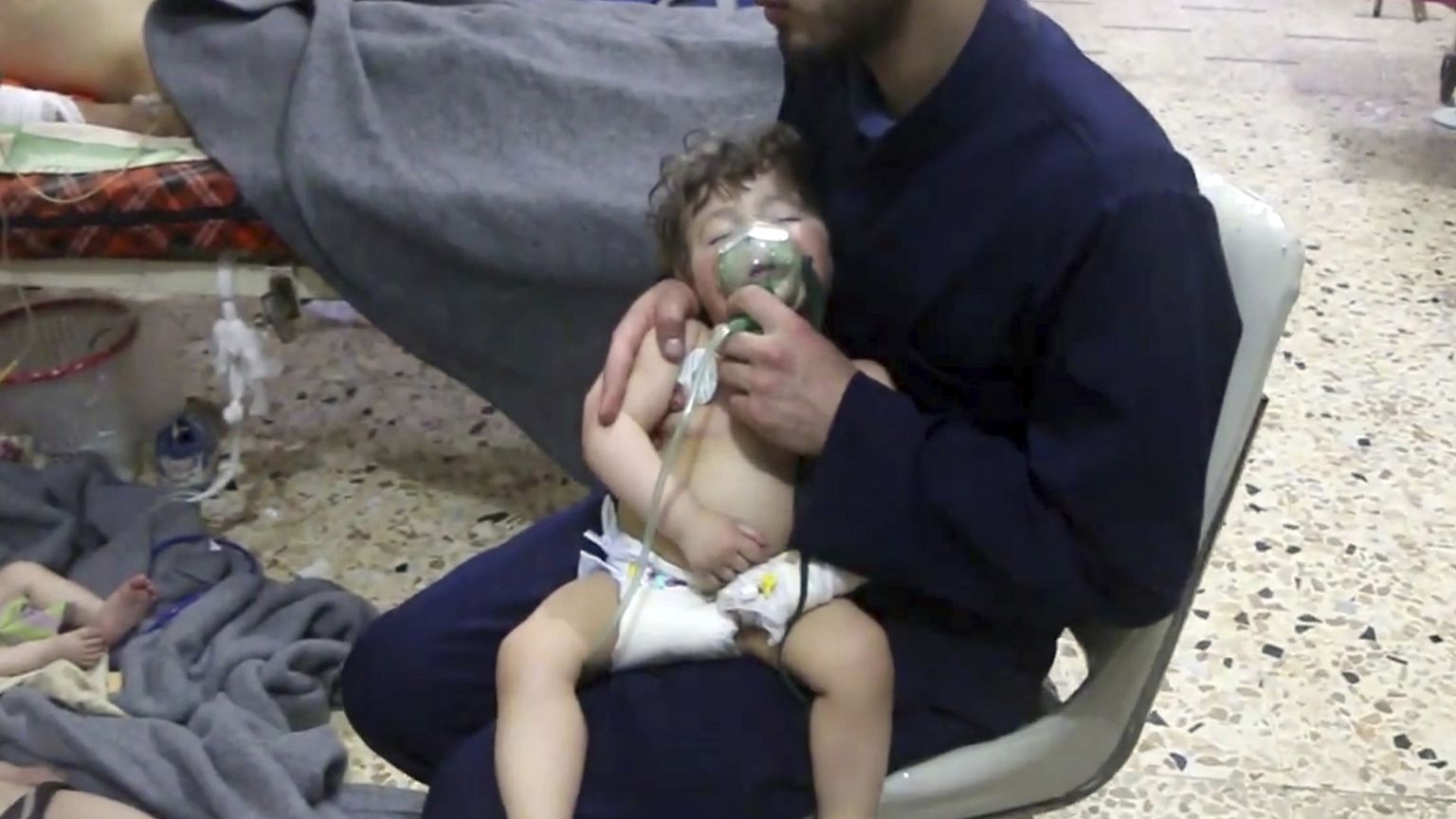 Image: A medical worker giving a toddler oxygen through a respirator