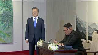 Image: North Korean leader Kim Jong Un signs a guest book as South Korean P