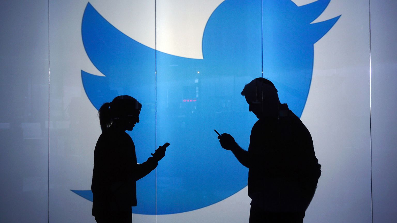 Image: People as silhouettes as they check mobile devices