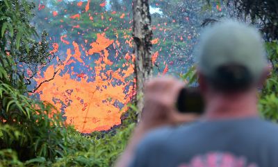 A man watches as lava spews from a fissure in the Leilani Estates subdivision on Friday.