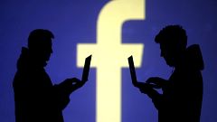 Image: FILE PHOTO: Silhouettes of laptop users are seen next to a screen pr