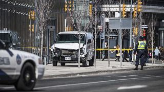 Image: Toronto police officers stand near a damaged van