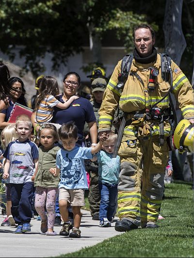 Firefighters and sheriff\'s deputies escort children from Academy on the Hill pre-k school in Aliso Viejo, Calif., after a fatal explosion nearby on May 15, 2018.