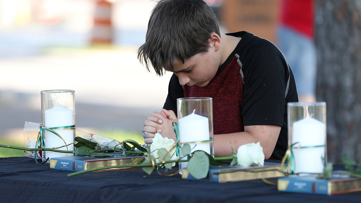 Image: A young boy prays during a vigil held at the Texas First Bank after 