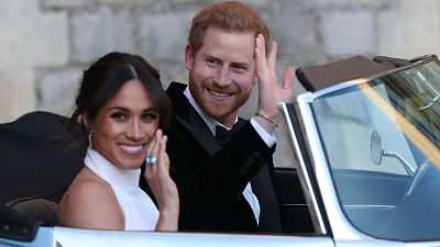 Britain\'s Prince Harry, Duke of Sussex, (R) and Meghan Markle, Duchess of Sussex, (L) leave Windsor Castle in Windsor on May 19, 2018 in an E-Type Jaguar after their wedding to attend an evening reception at Frogmore House.