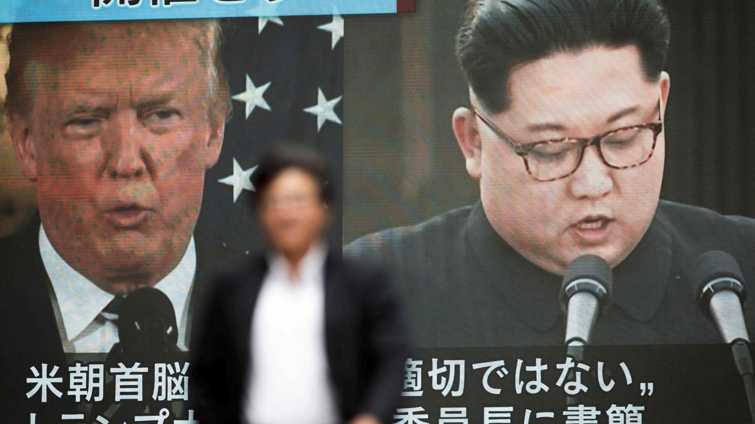 Image: A pedestrian walks in front of a screen in Tokyo showing Donald Trum