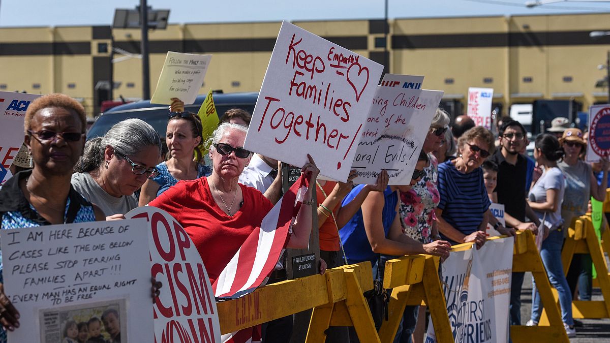 Image: Protesters hold signs in front of a Homeland Security facility in El