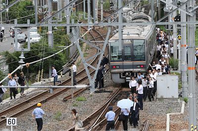 Train passengers walk along railroad tracks following an earthquake in Osaka, Japan, on Monday.