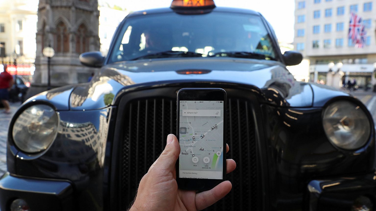 Image: A photo illustration shows the Uber app and a black cab in London,