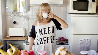 Caucasian woman drinking coffee in kitchen